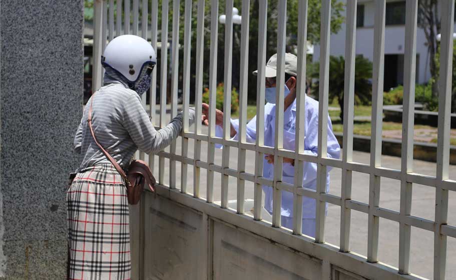 Bệnh viện Đà Nẵng bị phong tỏa, người nhà phải gửi đồ cho bệnh nhân qua cánh cổng sắt sáng 24/7. Ảnh: Đắc Thành.